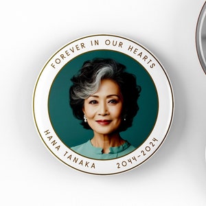 May include: Two white round buttons with a gold border and a teal background. The buttons feature a photo of a woman with gray hair and the text "Forever in our hearts" and "Hana Tanaka 2044-2024".