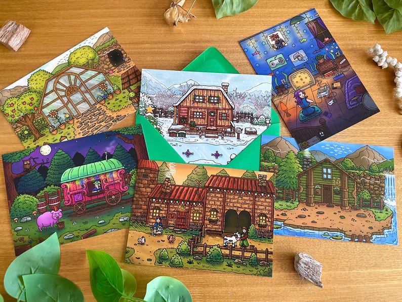 May include: A collection of illustrated postcards featuring colorful scenes of houses, cabins, and a greenhouse. The cards depict various settings, including a snowy landscape, a cozy interior, and a whimsical caravan. The cards are arranged on a wooden surface.