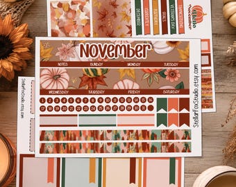 May include: A sticker sheet set for November featuring autumn-themed designs including pumpkins, fall leaves, and flowers. The sheets contain calendar headers, numbered date circles from 1 to 31, rectangular labels, and decorative strips in orange, brown, and green.
