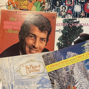 May include: A collection of vintage vinyl record covers featuring The Dean Martin Christmas Album, Christmas with Chet Atkins, and The Magic of Christmas. The covers display festive imagery including a Christmas tree, snowy landscapes, and portraits of musicians.