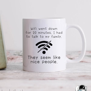 Puede incluir: Taza de café de cerámica blanca con un gráfico negro de un símbolo wifi con una línea diagonal que lo atraviesa. El texto dice "Wifi went down for 20 minutes, I had to talk to my family. They seem like nice people."
