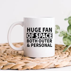 以下が含まれることがあります： 「Huge Fan Of Space Both Outer & Personal」という黒い文字が書かれた白いセラミックマグカップです。
