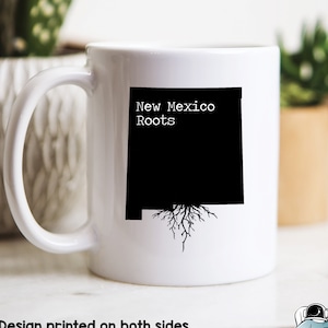 May include: White ceramic mug with a black outline of the state of New Mexico with roots growing from the bottom. The text "New Mexico Roots" is printed in black above the state outline.
