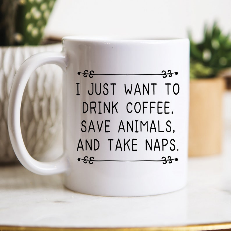May include: White ceramic coffee mug with black text that reads "I just want to drink coffee, save animals, and take naps."