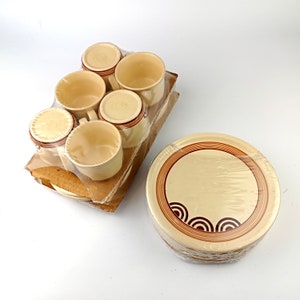 May include: Set of six cream-colored ceramic coffee mugs with brown geometric designs, packaged in plastic wrap, and a stack of cream-colored ceramic plates with brown geometric designs.