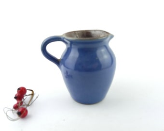 Um pequeno jarro feito de cerâmica escura coberto com esmalte azul