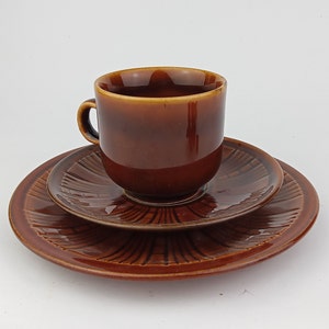 May include: A brown ceramic teacup and saucer set. The cup and saucer have a textured, striped design.