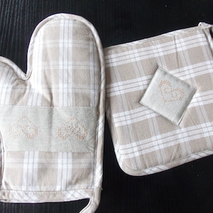 May include: A set of two beige oven mitts with a white checked pattern. The mitts have embroidered hearts on them.