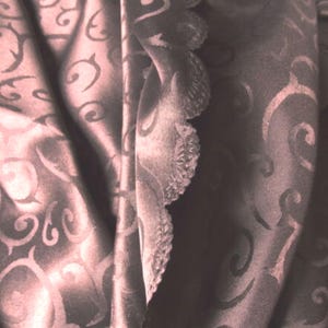 Puede incluir: Primer plano de una tela marrón con un patrón de espiral. La tela tiene un borde festoneado.