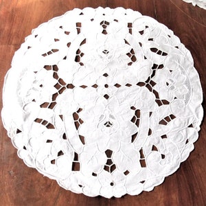 Pode incluir: Doily redondo de crochê branco com um delicado desenho floral.