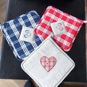 May include: Three pot holders with different patterns. One is blue and white checked, one is red and white checked, and one is a plain beige fabric with a red and white checked heart.