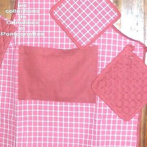 May include: A pink and white checkered apron with matching pot holders. The apron has a large pocket and the pot holders have a quilted design. The text "les collections de Carolines et Pomponettes" is visible.