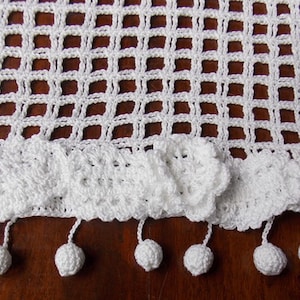 May include: White crocheted table runner with a scalloped edge and white pom-pom trim.