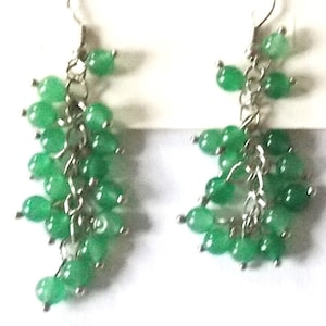 Könnte beinhalten: Ein Paar Hängeohrringe mit einer silbernen Kette und mehreren grünen Edelsteinperlen.