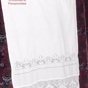 May include: White cotton curtain with a white lace trim. The curtain has a scalloped bottom edge and a text label that reads "les collections de Crinolines et Pomponettes".