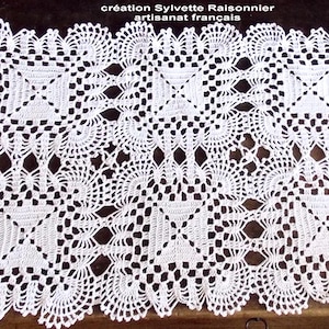 May include: White crocheted doily with a delicate, intricate pattern. The doily is square shaped and has a center design with four smaller squares. The text "création Sylvette Raisonnier artisanat français" is visible at the top of the image.