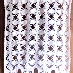Peut inclure: Rideau crocheté blanc avec un motif en losange et une frange de pompons blancs.