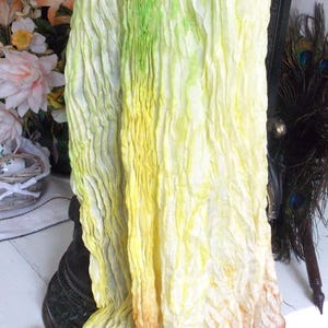 Peut inclure: Une longue écharpe fluide avec un dégradé de couleurs vert, jaune et marron. L'écharpe est faite d'un tissu doux et froissé et a un aspect délicat et éthéré.