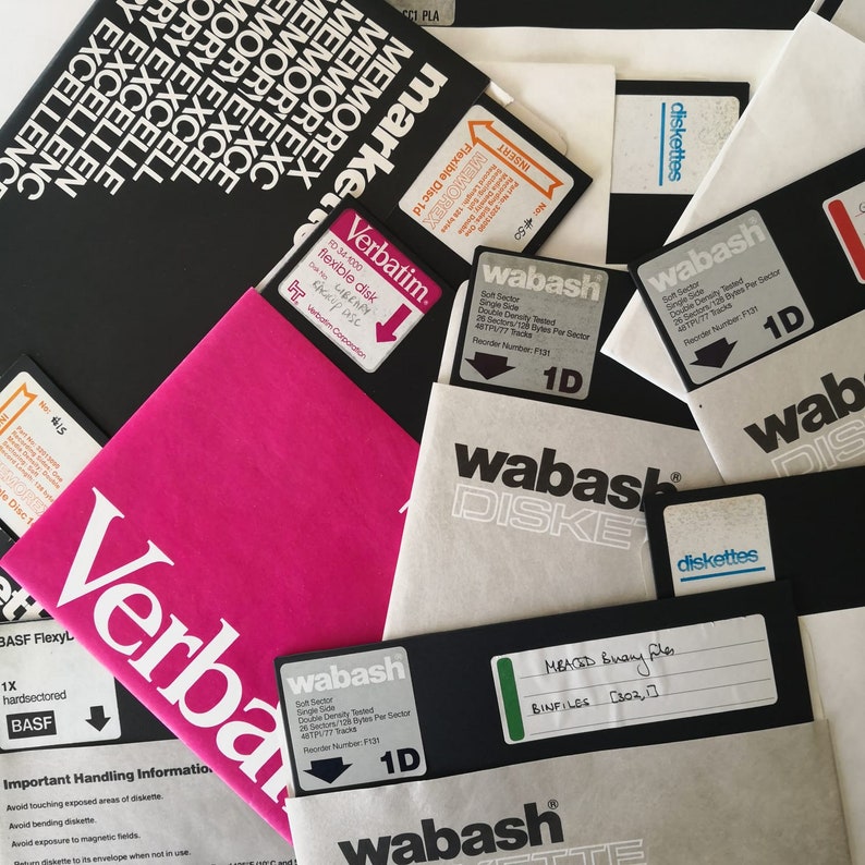 Pode incluir: Um close-up de uma cole&ccedil;&atilde;o de disquetes, incluindo as marcas Verbatim e Wabash. Os disquetes s&atilde;o de v&aacute;rias cores, incluindo rosa, branco e preto. Os disquetes s&atilde;o etiquetados com informa&ccedil;&otilde;es sobre sua capacidade e recursos. A imagem tamb&eacute;m inclui um r&oacute;tulo preto e branco com o texto "diskettes".