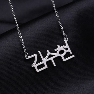 May include: A silver necklace with a pendant that says "감수현" in Korean characters.