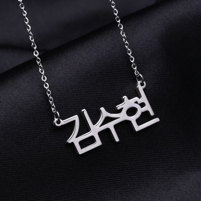 May include: A silver necklace with a pendant that says "감수현" in Korean characters.