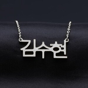 May include: Silver necklace with a Korean word pendant. The word is "잠수현".