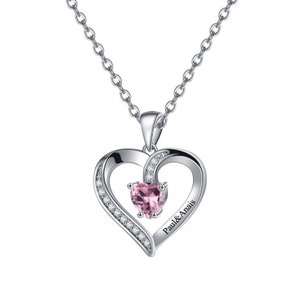 May include: Silver necklace featuring a heart-shaped pendant. The pendant has a smaller heart-shaped pink gemstone in the centre and is surrounded by smaller clear gemstones. The pendant is engraved with the text "Paul & Anais".