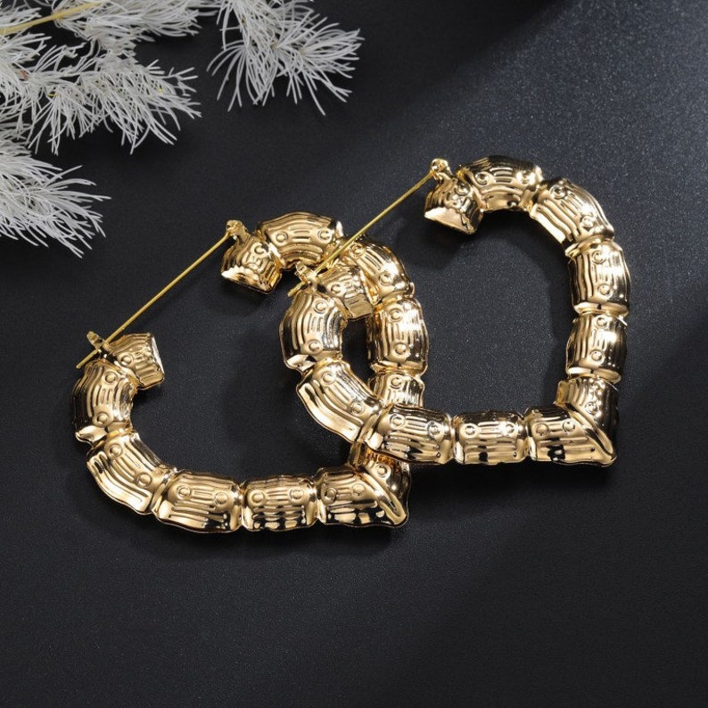 May include: A pair of large gold hoop earrings with a bamboo-like design. The earrings are made of metal and have a shiny finish.