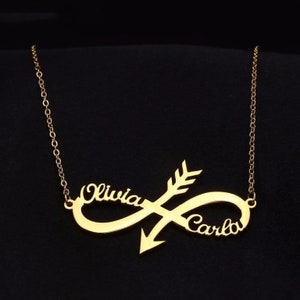 Puede incluir: Un collar dorado con un diseño de símbolo de infinito. El collar presenta los nombres "Olivia" y "Carlo" y está cruzado por una flecha. La cadena es delicada y el fondo es negro.