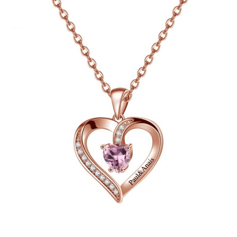 May include: Rose gold necklace with a heart-shaped pendant featuring a pink gemstone and a smaller heart with the inscription "Paul & Anais".