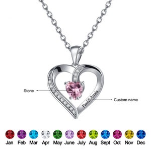 May include: A silver heart necklace with a pink gemstone in the centre. The necklace has a custom name engraved on the side, "Paul & Anais". The pendant is surrounded by small clear gemstones. The necklace comes with a choice of birthstone colours for the centre gemstone.