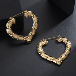 May include: A pair of gold heart-shaped hoop earrings with a bamboo-like texture.