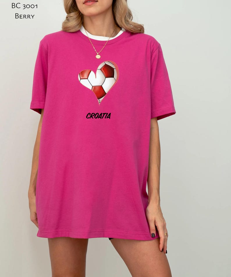 Op de afbeelding: Een roze T-shirt met een afbeelding van een voetbal in de vorm van een hart. De afbeelding bevat ook het woord "KROATI&Euml;".