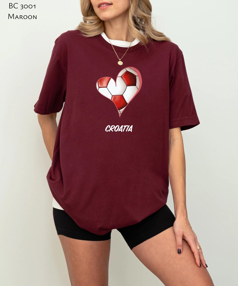 Op de afbeelding: Een maroon t-shirt met een wit hartontwerp met daarin een voetbal. De tekst "CROATIA" is onder het hart gedrukt.