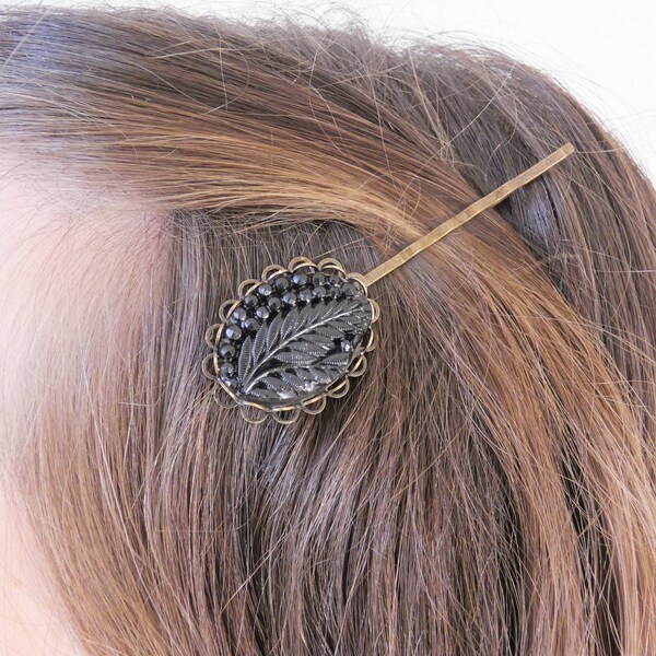 Barrette à chignon femme bronze décoré par un bijou noir brillant sculpté d'une feuille en résine. Cadeau artisanal unique pour femme.