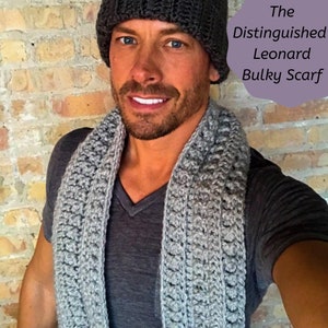 May include: A man wearing a gray knit beanie and a gray bulky scarf. The scarf has a textured pattern. The text "The Distinguished Leonard Bulky Scarf" is written in a purple box in the upper right corner of the image.
