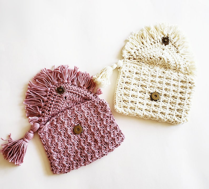 Puede incluir: Dos bolsos de crochet con detalles de flecos. Un bolso es rosa y el otro es blanco.