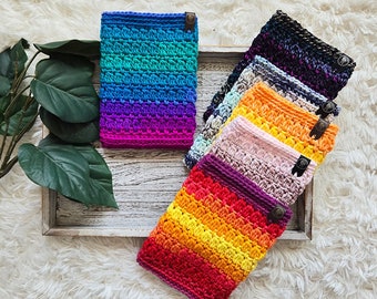 May include: A set of six colorful crocheted neck warmers, each with a different color gradient. The neck warmers are arranged in a fan shape on a wooden tray.