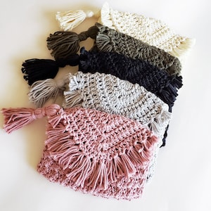 Puede incluir: Un conjunto de seis bolsas de crochet en varios colores, incluyendo rosa, gris, negro, verde y blanco. Cada bolsa tiene un borde de flecos y una borla.