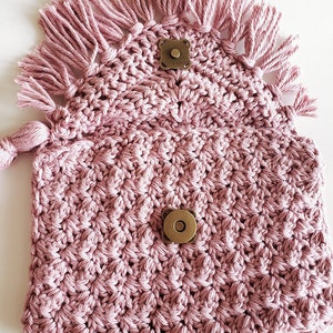 Puede incluir: Una bolsa de crochet rosa con un dise&ntilde;o texturizado y detalles de flecos. La bolsa tiene dos cierres magn&eacute;ticos de lat&oacute;n.