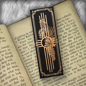 May include: A black bookmark with a gold design featuring a stylized floral motif and the text "when suddenly close by her. arkable in that; out of the way "Oh dear! Oh hen she thought her that she ought at the time it all when the Rabbit waistcoat-pocket, and ed on, Alice started oss her mind that she bit with either a waist- o take out of it, an he ran across the fie me to see it pop dow e hedge. down went Alice ver once considering how in the wo t again. le went straight on like dipped suddenly ot a momen he fo"