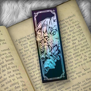 May include: A holographic bookmark featuring a colorful illustration of a woman with a knife in her mouth. The bookmark has a black background with a white border. The text "when suddenly close by her. arkable in that; out of the way "Oh dear! Oh hen she thought her that she ought at the time it all when the Rabbit waistcoat-pocket, and ed on, Alice started oss her mind that she bit with either a waist- o take out of it, an he ran across the fie me to see it pop dow e hedge. down went Alice how in the wo ver once considering le went straight on like dipped suddenly tamome be fo" is visible on the bookmark.