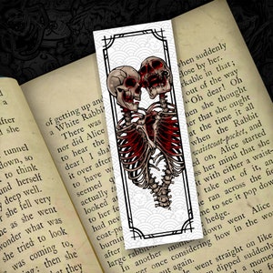 May include: A bookmark featuring a black and white illustration of two skeletons embracing. The skeletons are red and have a detailed anatomical design. The background is white with a black and white pattern.