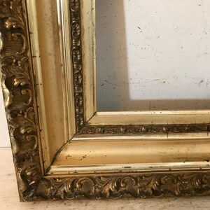 May include: A gold-colored picture frame with ornate detailing. The frame is made of wood and has a distressed finish.