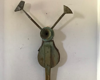 May include: A rustic, wooden, and metal sculpture with two long arms and a round, wooden body. The arms are made of metal and have a flat, triangular shape at the end. The body is made of wood and has a round, wooden shape. The sculpture is painted in a light brown color.