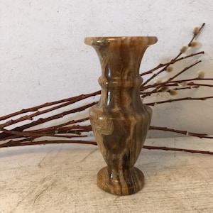 May include: A small, brown and white striped, marble vase with a rounded base.