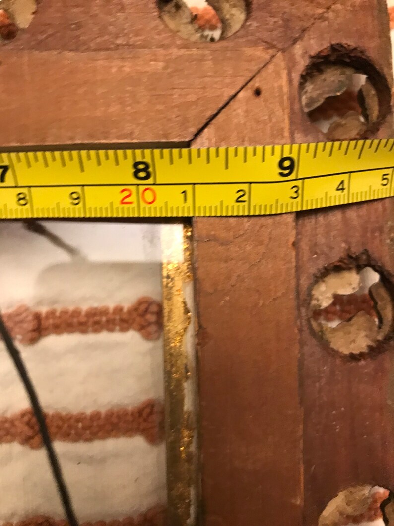 K&ouml;nnte beinhalten: Nahaufnahme eines Holzbildrahmens mit einem gelben Ma&szlig;band, das darum gewickelt ist. Das Band zeigt "20 1 2 3 4 5".