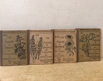 May include: Four vintage book covers with illustrations of flowers. The covers are brown with black text and illustrations. The titles are "Les Fleurs de Jardins" by A. Guillaumin. The books are numbered XXIX, XVII, XVI, and XV.