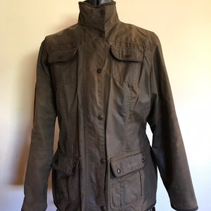 May include: A dark green, button-up jacket with multiple pockets. The jacket has a stand-up collar and a zipper closure.