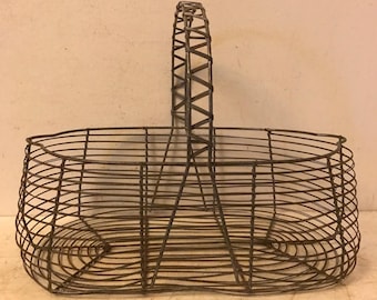 May include: A vintage wire basket with a woven handle. The basket is oval shaped and has a wire mesh design.
